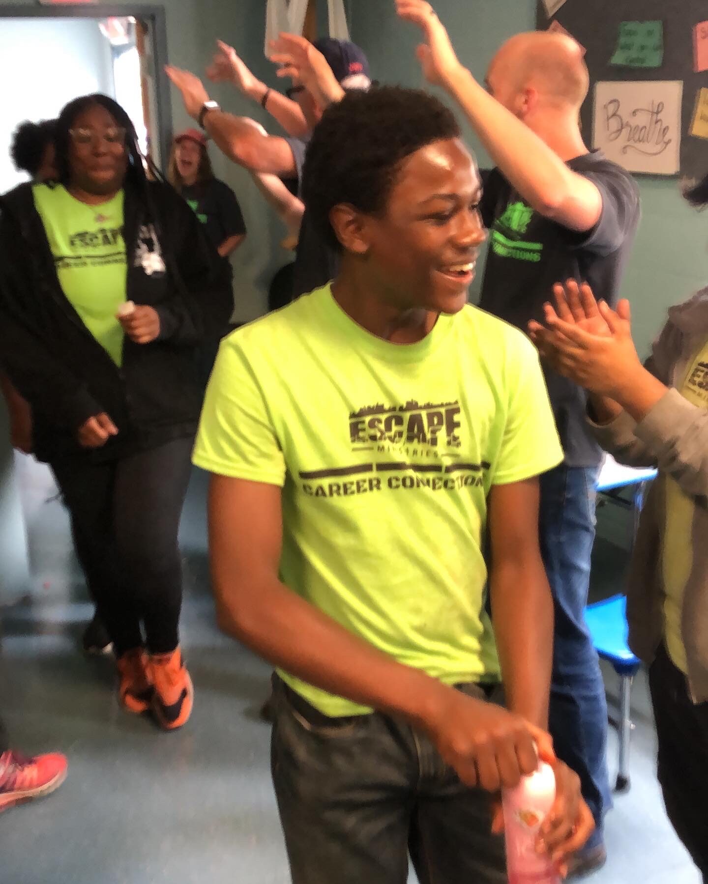 Young man smiling and walking in a lively indoor setting.