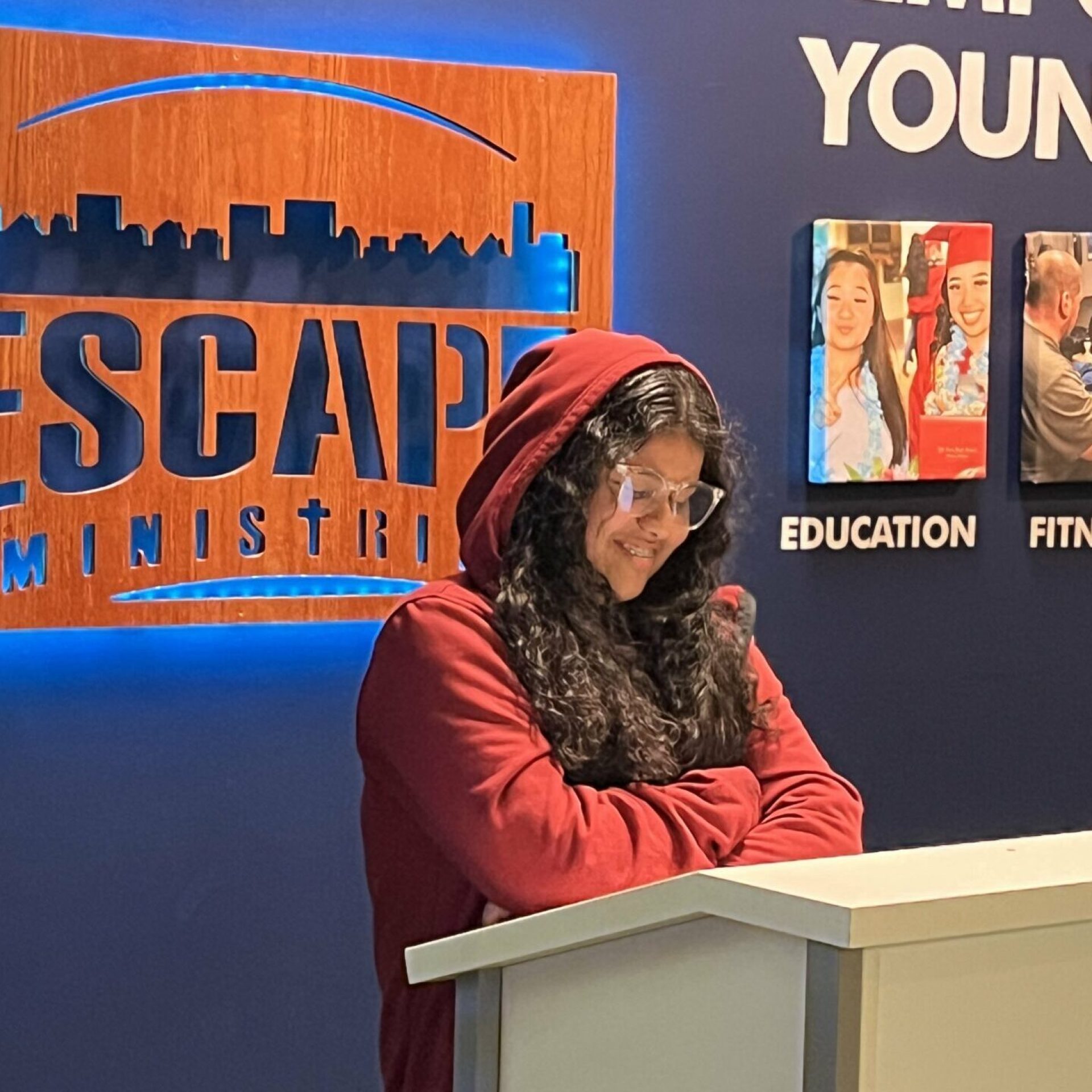 Woman speaking at a podium in front of an Escape Ministries sign.